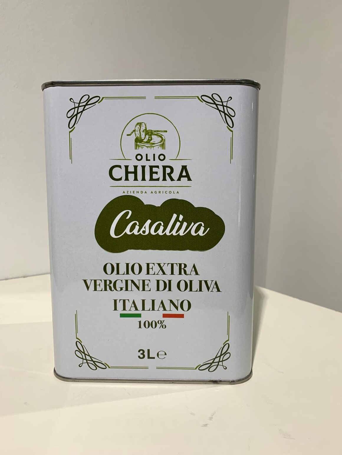 Bottiglie di olio extravergine monovarietale con sfondo di uliveto